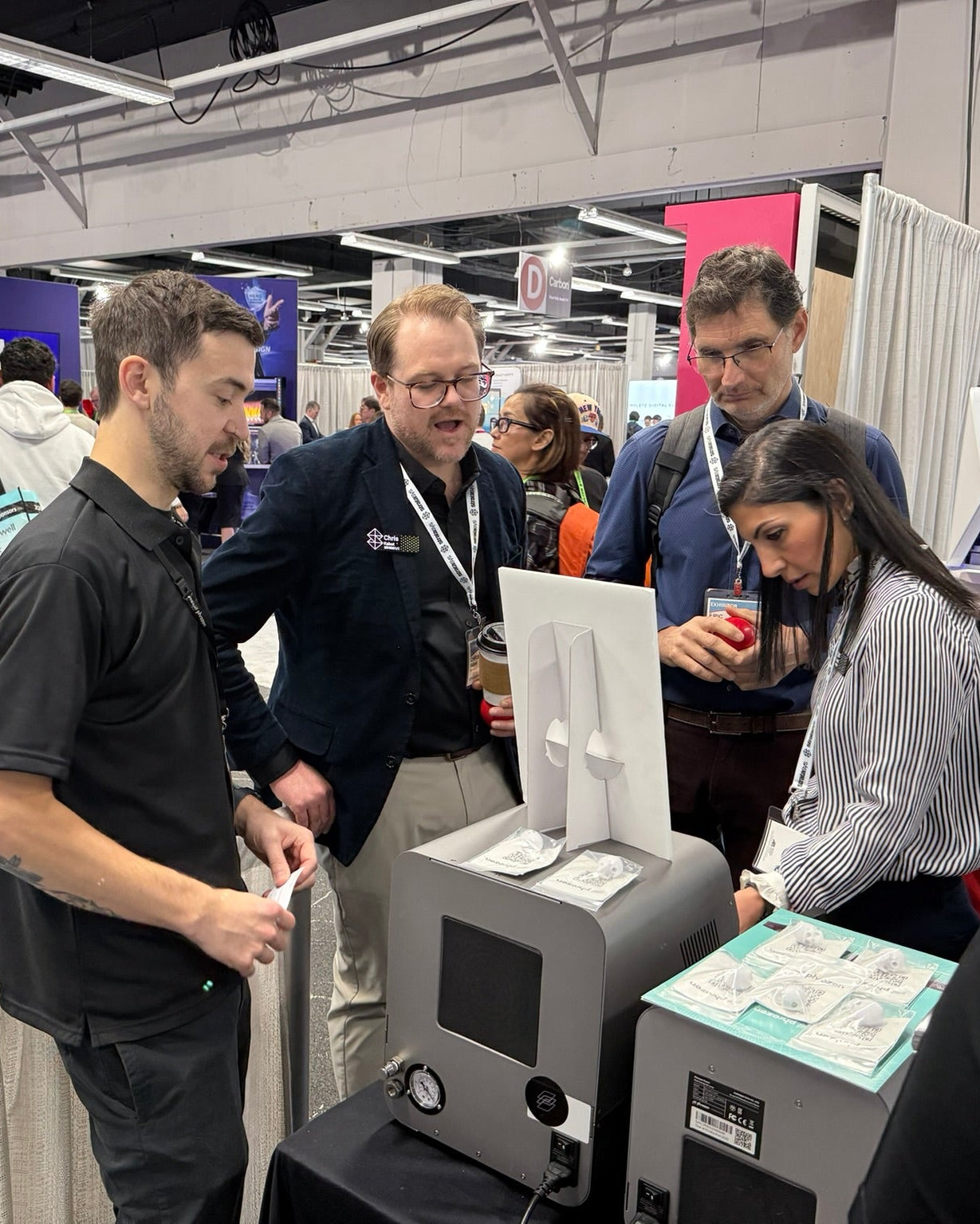 Dental professionals gather around the V-CURE vacuum curing station at LMT LAB DAY 2026, exploring its simplified workflow and vacuum curing technology for biocompatible dental applications.